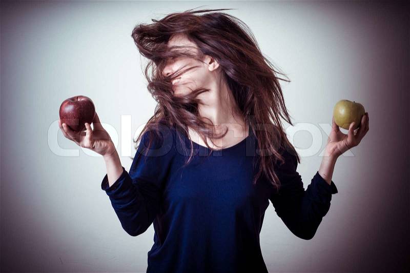 Beautiful woman choosing red or yellow apples on gray background, stock photo