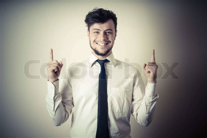 Stylish modern guy with white shirt pointing on gray background, stock photo