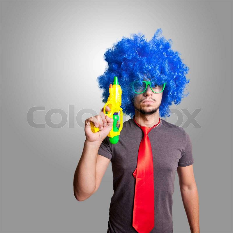 Funny guy with blue wig and water gun on grey background, stock photo