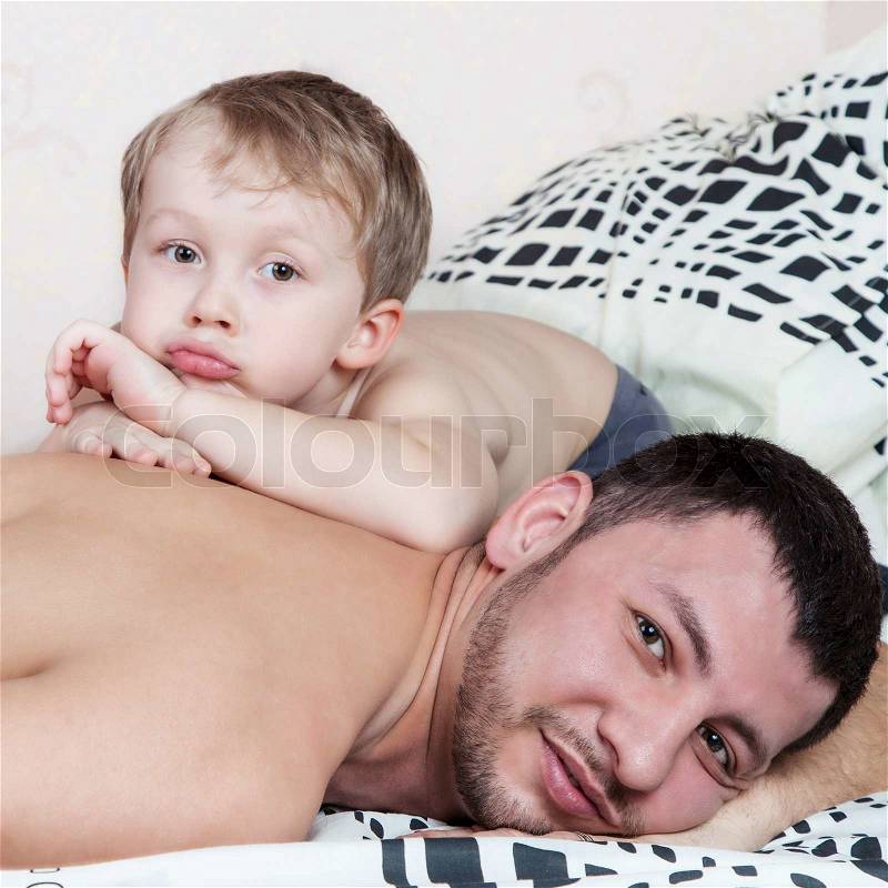 Son lying on the back of his father, stock photo