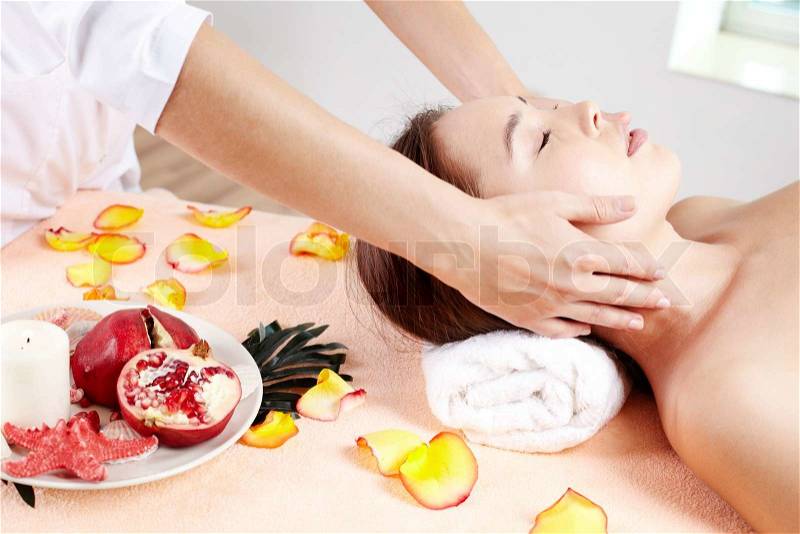 Massage therapist helping young woman accumulate energy after a workweek, stock photo