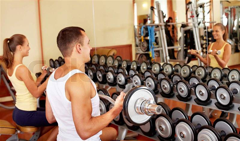 Image of sporty man and woman training with barbells , stock photo