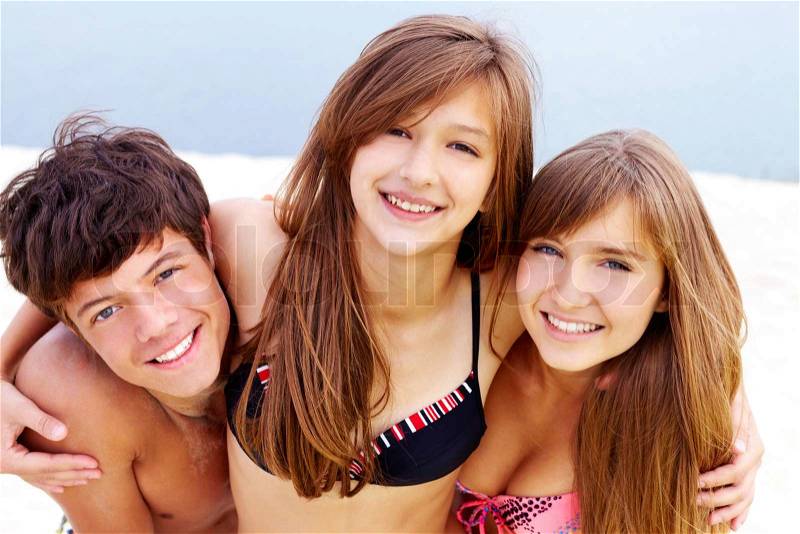Portrait of happy teenage guy and two pretty girls, stock photo