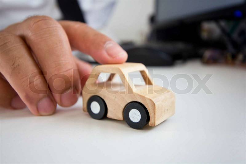 Businessman holding a wooden car on a table, stock photo