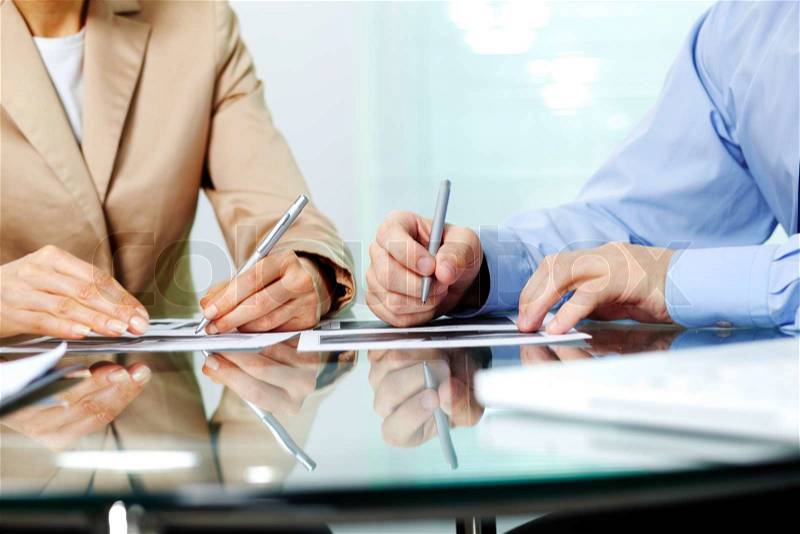 Business people sitting together and making notes at workplace, stock photo