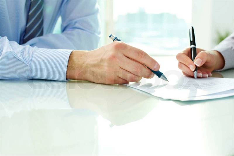 Two business partners signing a document, stock photo