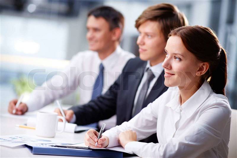 Three business people sitting at seminar, the focus is on woman, stock photo
