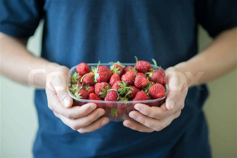 Plate of strawberries in hands, stock photo