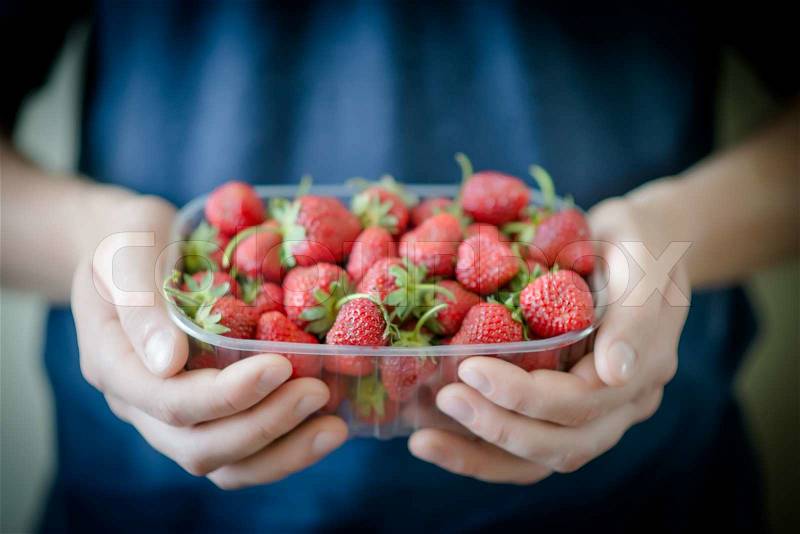 Plate of strawberries in hands, stock photo