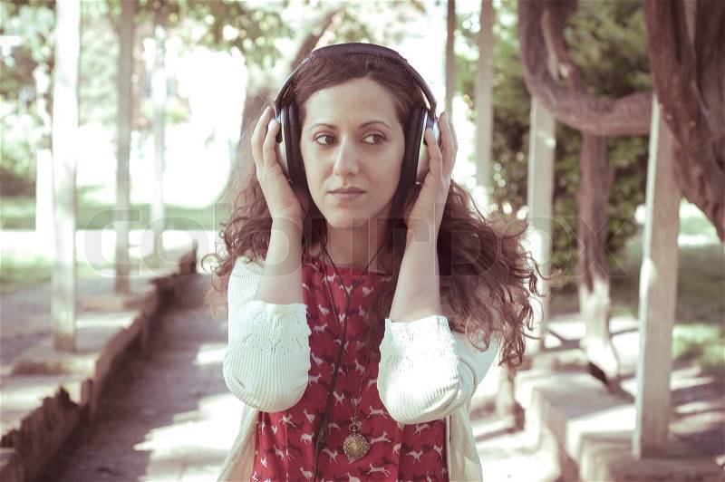 Vintage hipster eastern woman with headphones in the park, stock photo