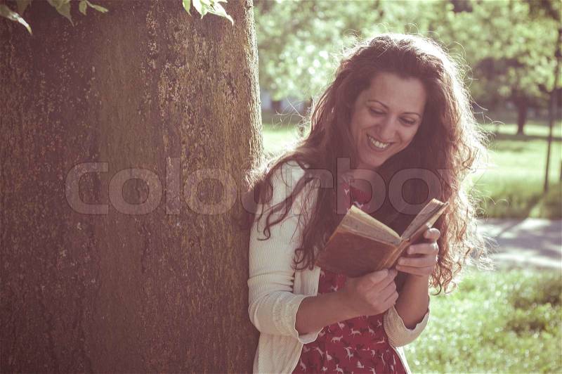 Eastern hipster vintage woman reading book in the park, stock photo