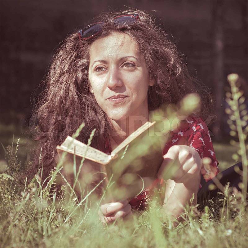 Eastern hipster vintage woman reading book in the park, stock photo