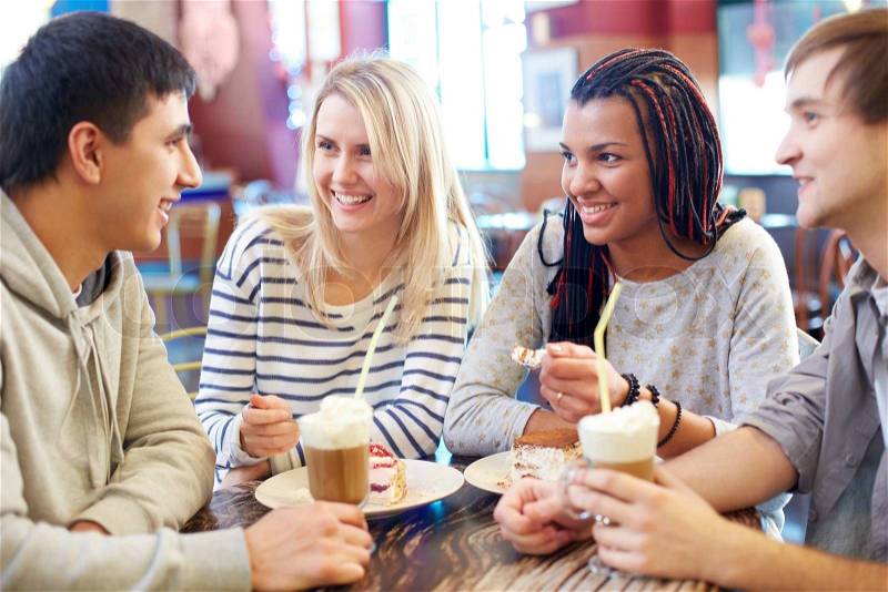 Image of teenage friends chatting while spending time in cafe, stock photo