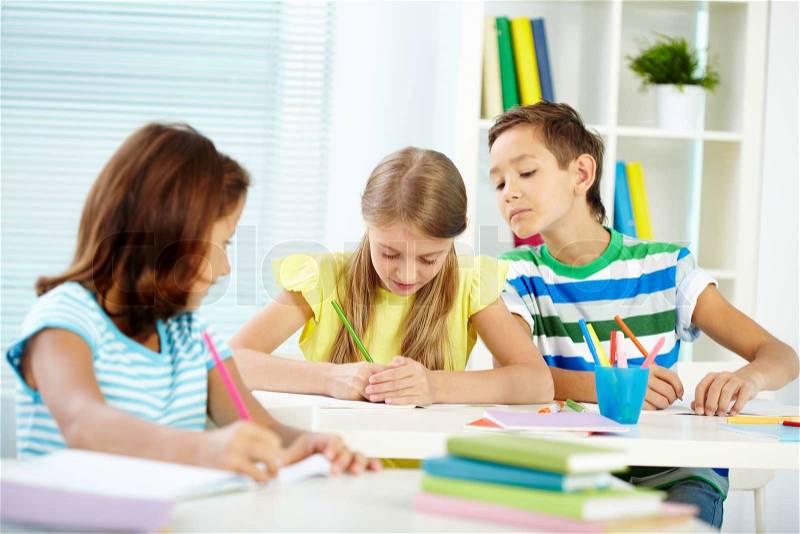 Portrait of cute schoolkids drawing at lesson, stock photo