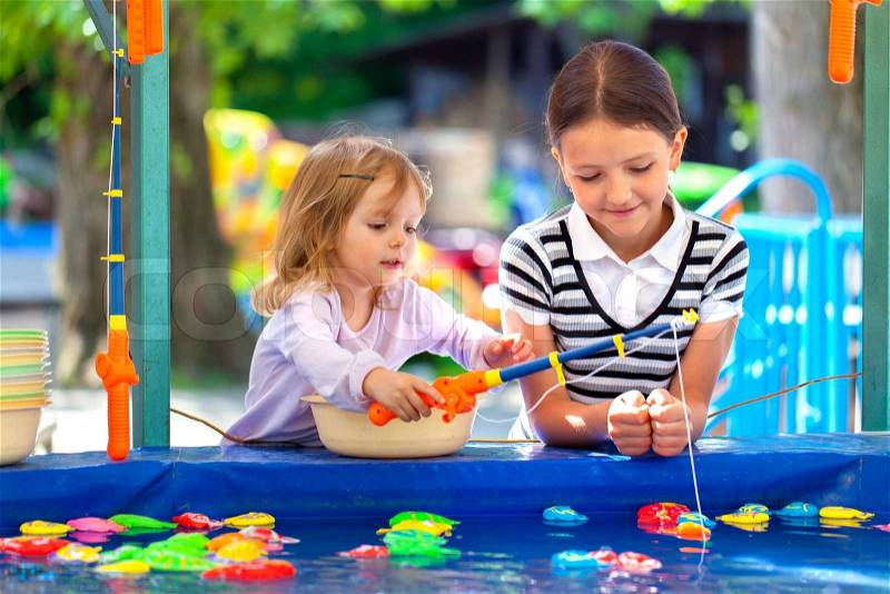 Two sisters, fishing in the paddling pool, stock photo