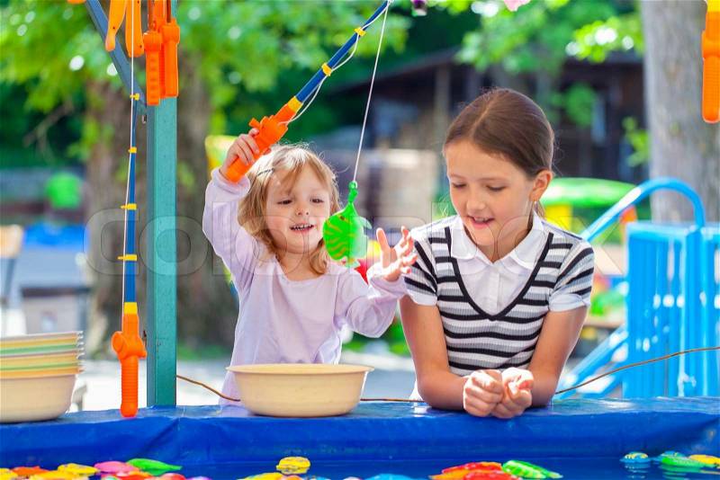 Two sisters, fishing in the paddling pool, stock photo