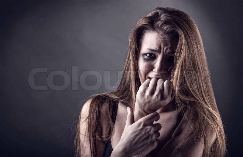 Young crying woman on a dark background, stock photo