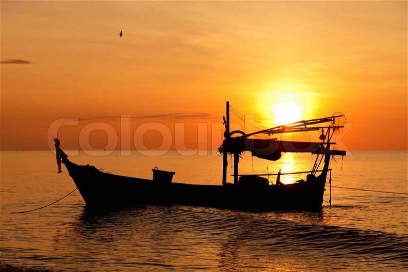 Silhouette of fishing boat at sunset, stock photo