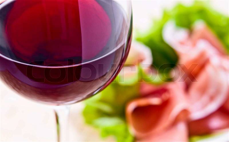 Glass with red wine and ham with salad , focus on a foreground, stock photo