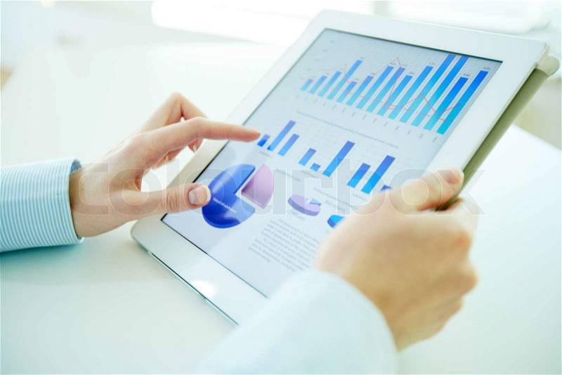 Business person analyzing financial statistics displayed on the tablet screen, stock photo