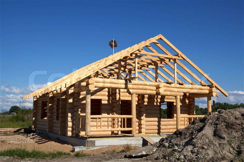 New house built from logs against blue sky, stock photo