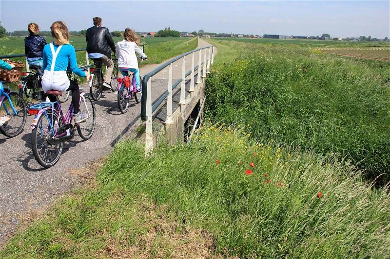 The school youth in one group are biking over the bridge and going to school in the summer, stock photo