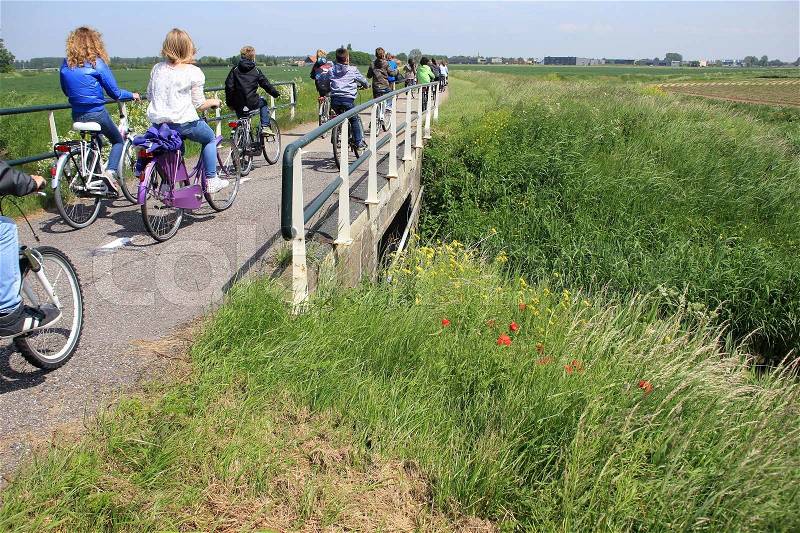 A group of bikers, boys and girls, cycling over the bridge and going to school in the summer, a nice trip, stock photo