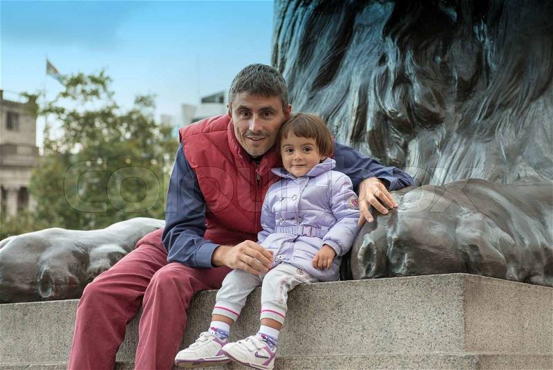 Baby with father playing at the base of Nelson Column in Trafalgar Square - London, stock photo
