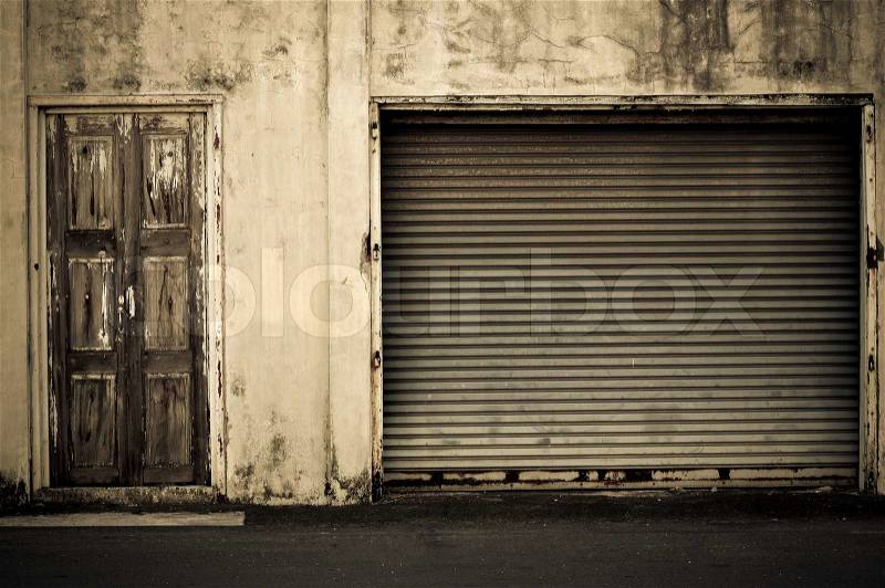 Illuminated grunge metallic roller shutter door near wooden door vintage style, stock photo