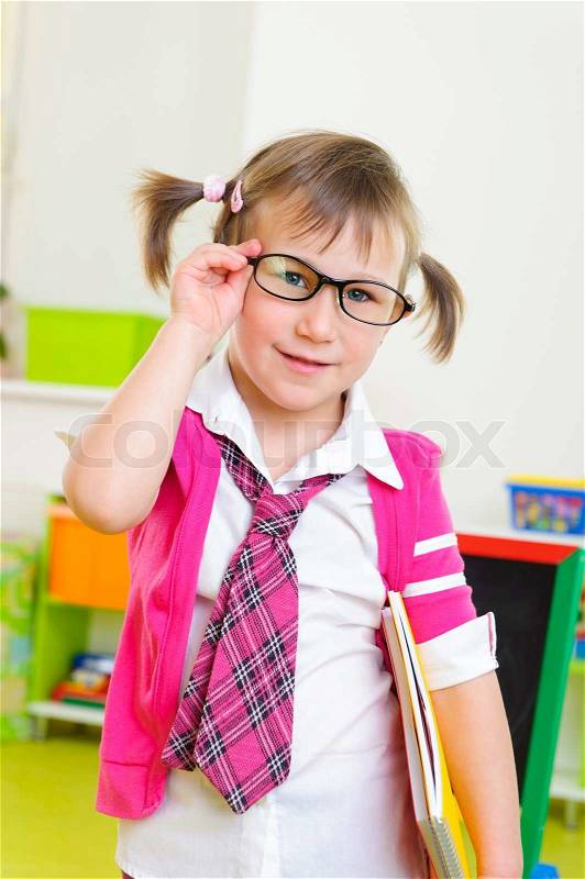 Cute little girl win eyeglasses and necktie with notebook folder, stock photo