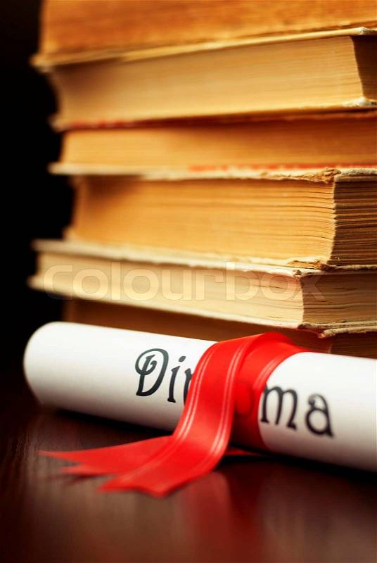 Diploma with red ribbon and a stack of books, stock photo