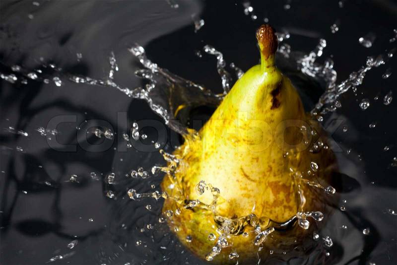 Fresh yellow pear splashing into water with water bubbles, stock photo
