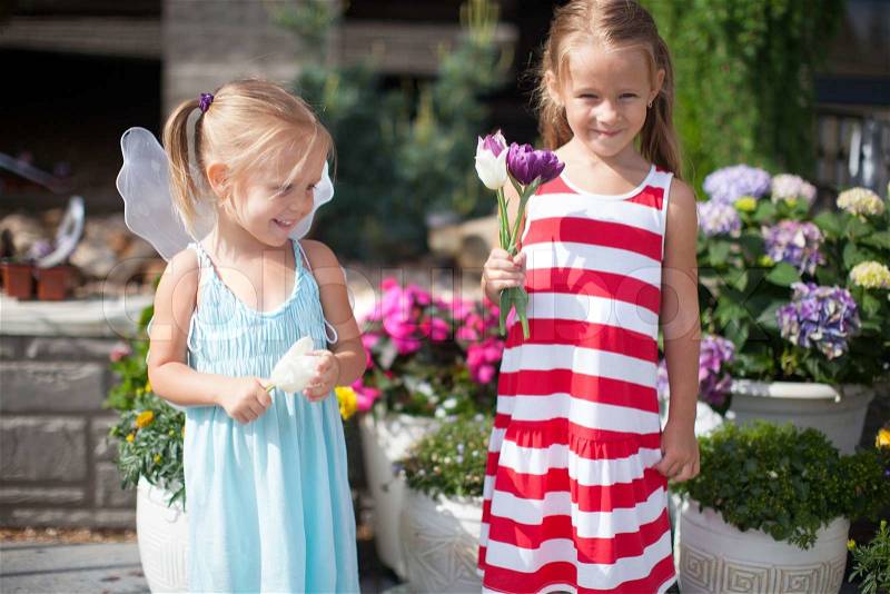 Sweet little girls in a country yard with flowers in their hands, stock photo
