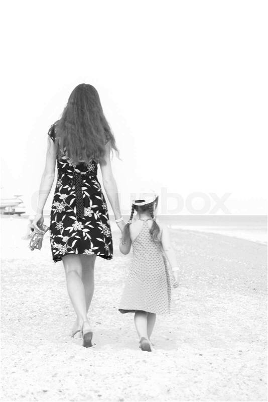 Mother and daughter walking on beach Black and white, stock photo