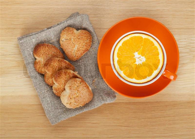 Cup with orange and heart shaped cookies on wooden table. View from above, stock photo