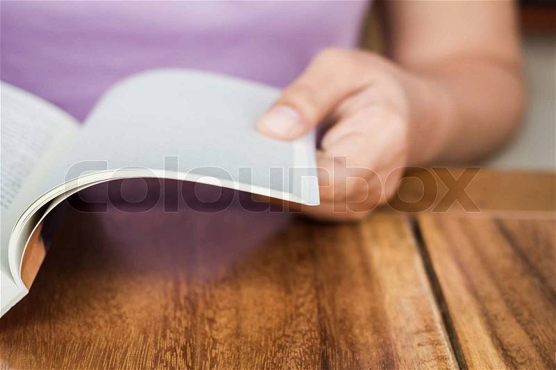 Closeup hand open book on wood table, stock photo