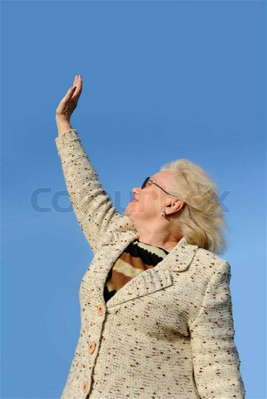 Happy senior woman waving on sky background, stock photo