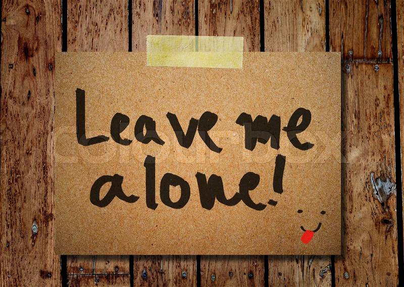 Note paper and clothes peg on a wooden background with leave me alone message, stock photo