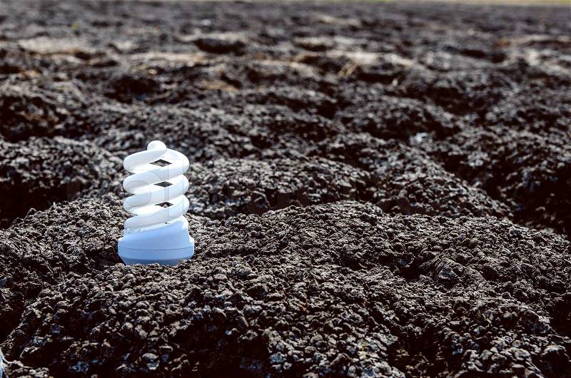 Energy saving light bulb on dark desert, stock photo