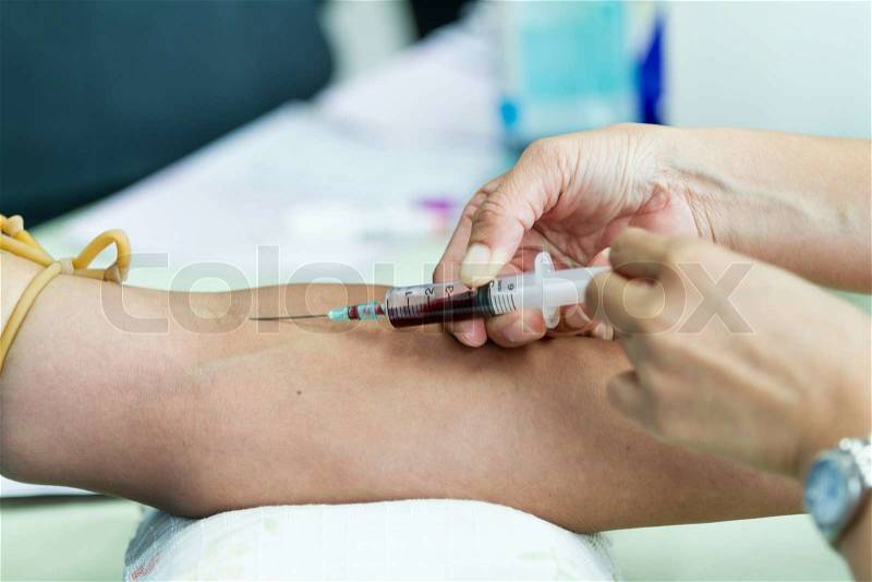 Doctor drawing blood sample from arm for blood test, stock photo