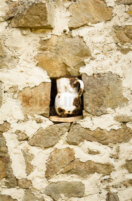 Detail of vintage metalic pitcher in a niche in stone wall, stock photo