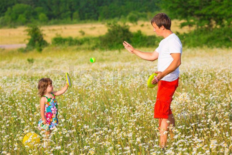 Father playing with daughter on the camomile meadow, stock photo