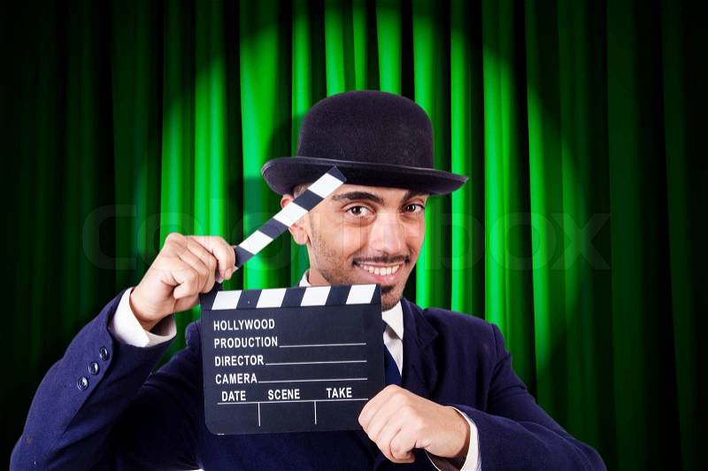 Man with movie clapper on curtain background, stock photo