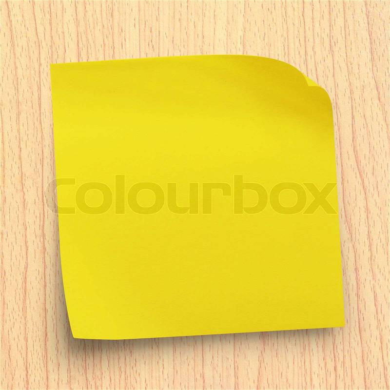 Yellow sticker note on plywood wall, stock photo