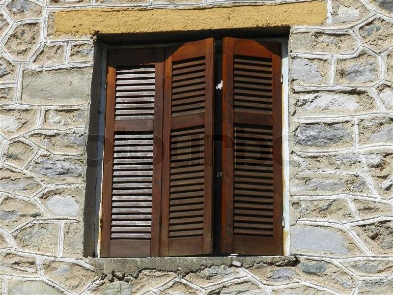 Closed wooden window with shutters on a old stone wall, stock photo