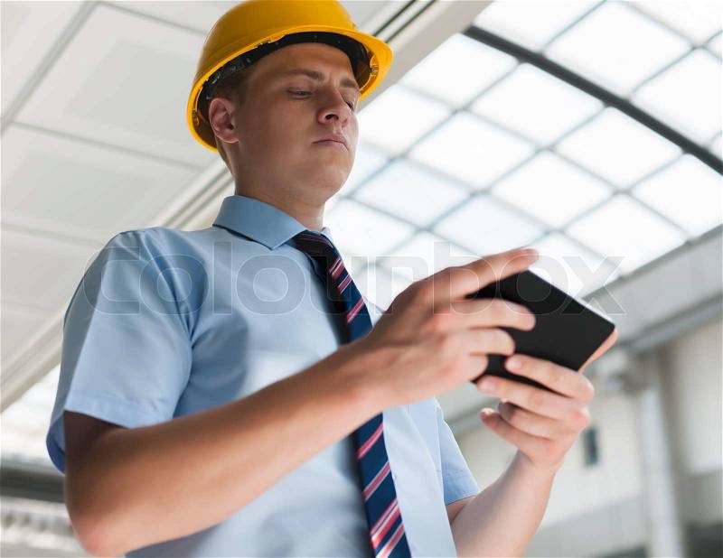 Engineer in a helmet with a digital tablet, stock photo