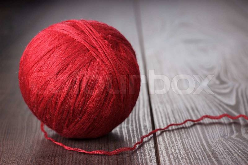 Red ball of threads on wooden table, stock photo