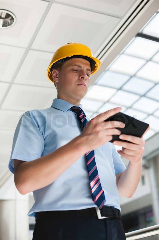 Engineer in a helmet with a digital tablet, stock photo