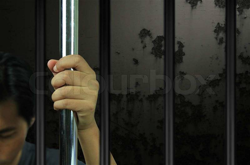 Hands of the prisoner on the prison, stock photo