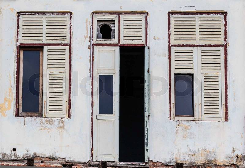 Abandoned Facade White Building showing ruined Wooden Door and windows, stock photo